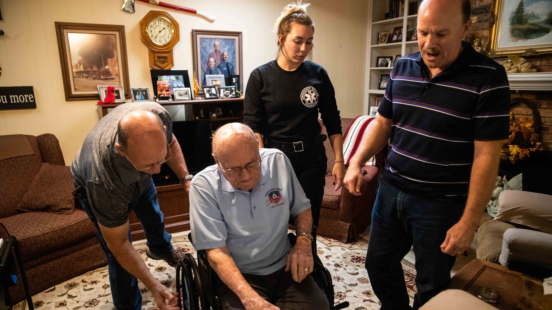 A living history of Austin, TX, firefighters: (from left) Emmett Glosson's son, Joe, his great-grandaughter Tiffany Gell; and grandson Kevin Gell, help Emmett sit in his wheelchair at his home.