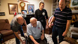 A living history of Austin, TX, firefighters: (from left) Emmett Glosson's son, Joe, his great-grandaughter Tiffany Gell; and grandson Kevin Gell, help Emmett sit in his wheelchair at his home. A living history of Austin, TX, firefighters: (from left) Emmett Glosson's son, Joe, his great-grandaughter Tiffany Gell; and grandson Kevin Gell, help Emmett sit in his wheelchair at his home.