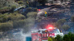 A CAL FIRE firefighter mops up a hot spot on hillside along Highway 18 in San Bernardino, CA., on Thursday.