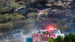A CAL FIRE firefighter mops up a hot spot on hillside along Highway 18 in San Bernardino, CA., on Thursday.