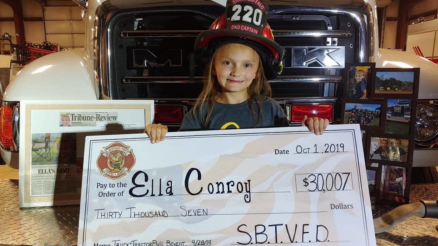 Ella Conroy, 6, shows off a check for the $30,007 raised by the South Buffalo, PA, Fire Department.