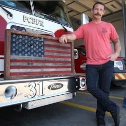 Panama City, FL, firefighter Daryl Paul stands with a flag he made from discarded fire hoses.