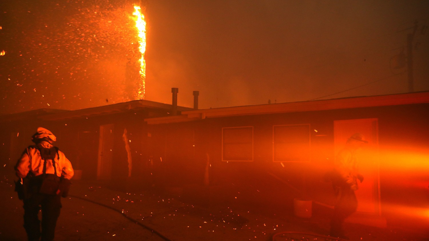 Firefighters walk near homes that are threatened by the Woolsey fire in Malibu, CA.