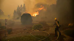 A firefighter pulls a hose line during efforts to contain the Kincade Fire in Windsor, CA, on Nov. 3, 2019.