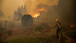 A firefighter pulls a hose line during efforts to contain the Kincade Fire in Windsor, CA, on Nov. 3, 2019.