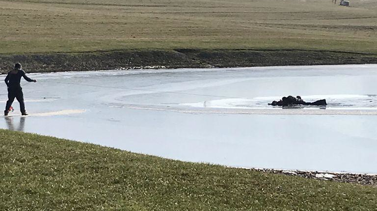 East Wayne, OH, firefighters work to rescue a man and his two grandsons after they fell through ice at a small pond near the village of Dalton on Sunday.