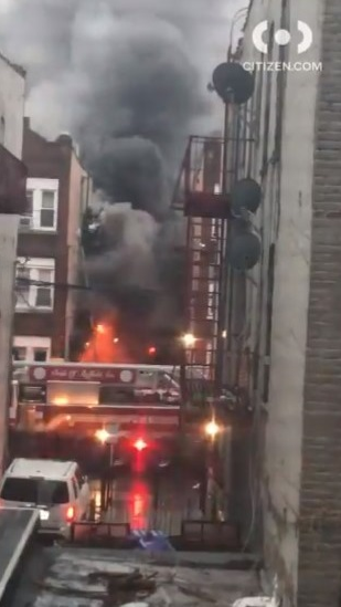 FDNY firefighters help residents on the fire escape of a burning three-story apartment building early Monday in the East New York neighborhood of Brooklyn.