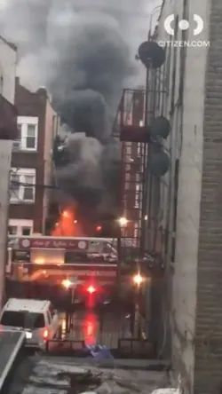 FDNY firefighters help residents on the fire escape of a burning three-story apartment building early Monday in the East New York neighborhood of Brooklyn.