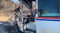 A Osawatomie firefighter hoses down the remains of the burning mail truck.