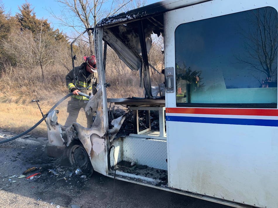 A Osawatomie firefighter hoses down the remains of the burning mail truck.