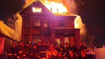 Detroit firefighters pose in front of a burning home on New Year's Eve in a photo that was posted on social media.