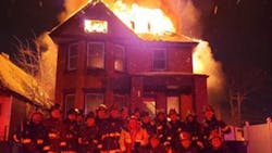 Detroit firefighters pose in front of a burning home on New Year&apos;s Eve in a photo that was posted on social media.