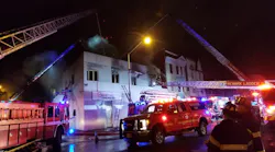Around 65 Newark, NJ, firefighters battled a two-alarm blaze that broke out at a vacant commercial building and spread to a nearby structure late Friday.