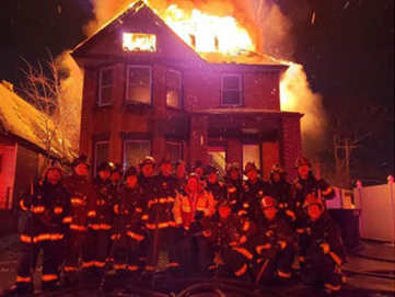 Detroit firefighters pose in front of a burning home on New Year's Eve in a photo that was posted on social media.