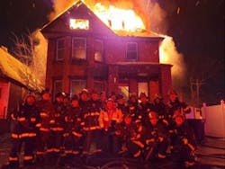 Detroit firefighters pose in front of a burning home on New Year&apos;s Eve in a photo that was posted on social media.