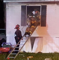 Firefighters remove the victim from the burning mobile home.