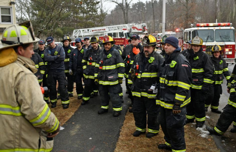 Under new protocol, firefighters listen to comments by a chief after they fought a 2-alarm fire at 63 Overlook Drive in Worcester. The fire displaced about 30 people on Feb. 18.