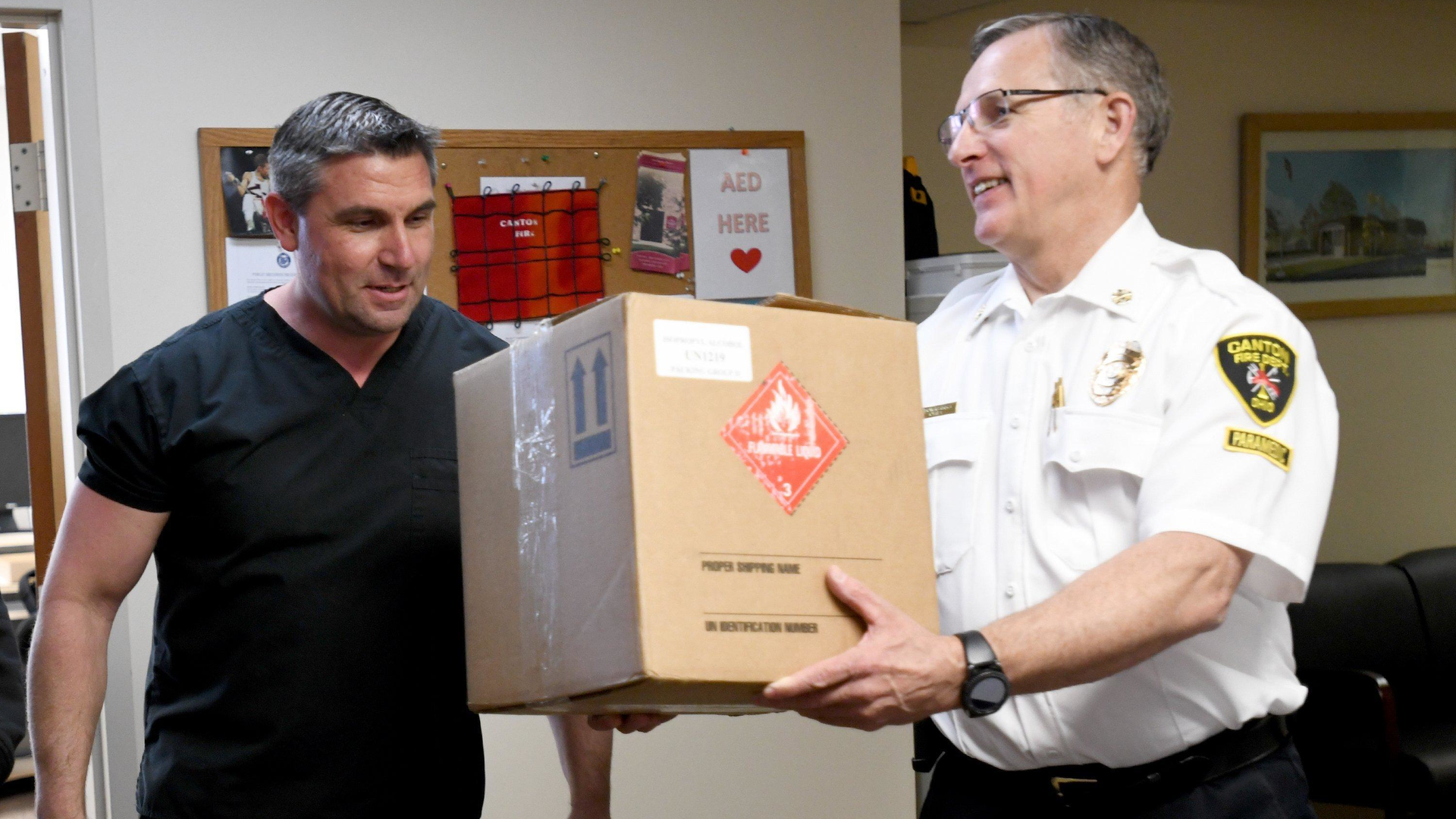 Former Canton, OH, firefighter/paramedic Rosario Carcione (left), who now is pharmacy manager at Compounding Pharmacy of Green, donated Monday bottles of hand sanitizer to Fire Chief Tom Garra..