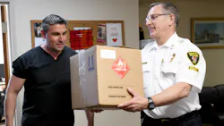 Former Canton, OH, firefighter/paramedic Rosario Carcione (left), who now is pharmacy manager at Compounding Pharmacy of Green, donated Monday bottles of hand sanitizer to Fire Chief Tom Garra..