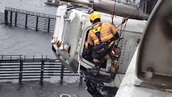 A Chesapeake, VA, firefighter rappels down the side of a bridge to rescue a truck driver whose tractor-trailer cab was hanging 70 feet above the Elizabeth River after a crash Monday.