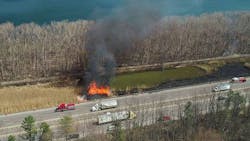 Firefighters from multiple departments trudged through mud and battled 35-foot flames to put out a brush fire along Interstate 690 West near Geddes on Monday.