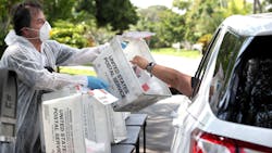 Jill Blasenstein picks up gloves, masks, and hand sanitizer from retired Boynton Beach, FL, firefighter and paramedic Luis Garcia at his home-based drive-through service. Jill Blasenstein picks up gloves, masks, and hand sanitizer from retired Boynton Beach, FL, firefighter and paramedic Luis Garcia at his home-based drive-through service.