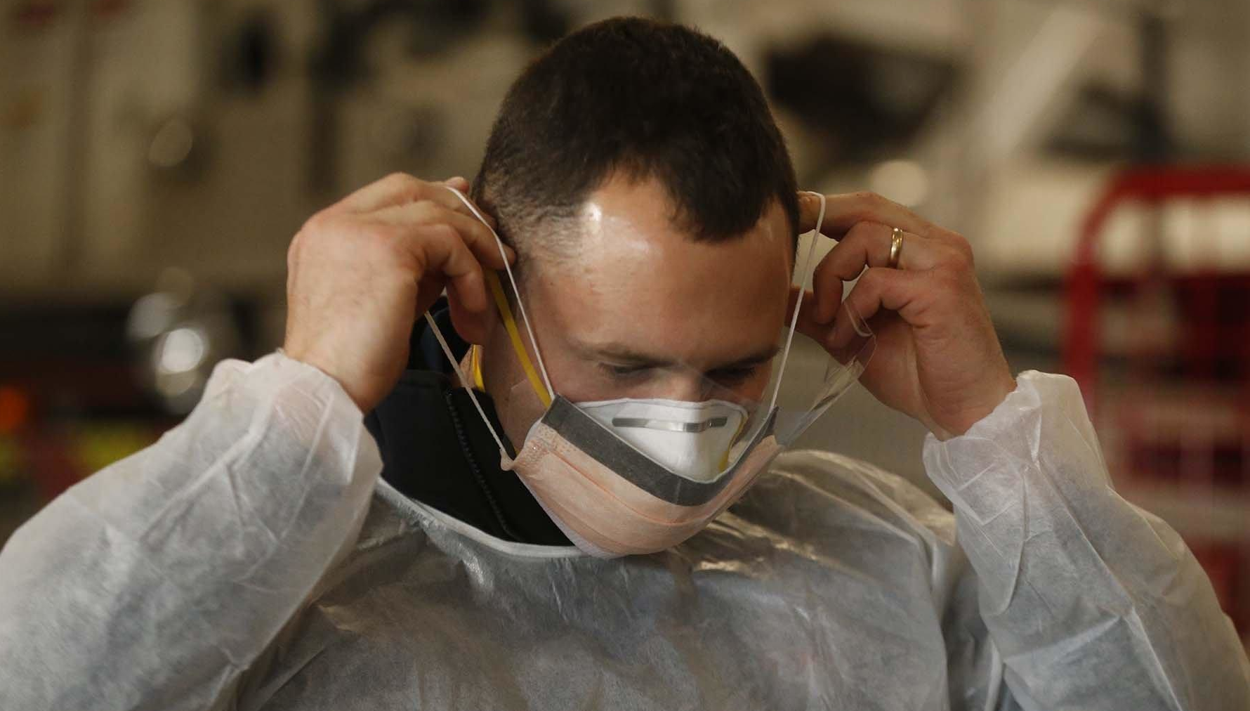 Sam Sprankle, a firefighter/paramedic with the Green, OH, Fire Department puts on the N95 mask and surgical mask that he and other EMS personnel will wear while working with COVID-19 patients.