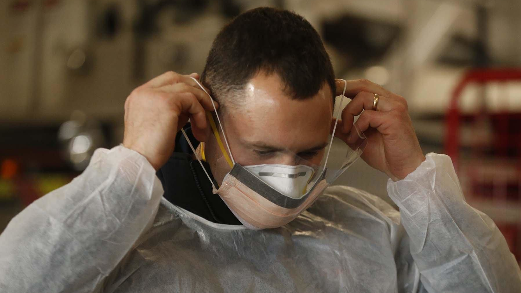 Sam Sprankle, a firefighter/paramedic with the Green, OH, Fire Department puts on the N95 mask and surgical mask that he and other EMS personnel will wear while working with COVID-19 patients.