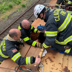 Firefighters use rope to secure the man between the load of beams before he is pulled from the train. Firefighters use rope to secure the man between the load of beams before he is pulled from the train.