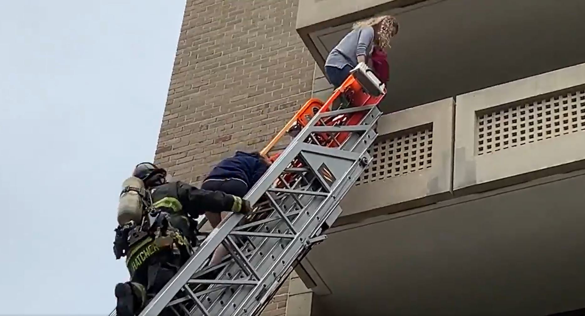 A D.C. Fire and EMS firefighters helps two occupants to safety from an aerial ladder.