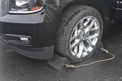Plastic wheel chocks that are connected by a rope are positioned at the front and rear of one tire to prevent unwanted forward and rearward movement.