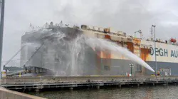 Jacksonville, FL, firefighters spray the sides of an auto-hauling cargo ship as fire continues to burn inside.