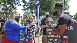 Hingham, MA, resident Anne Pungitore (left) talks Tuesday with Black Lives Matter protester Tru Edwards (right) who came from Boston to counter protest a rally held to object to town officials asking for the removal of &apos;thin blue line&apos; flags from fire apparatus.