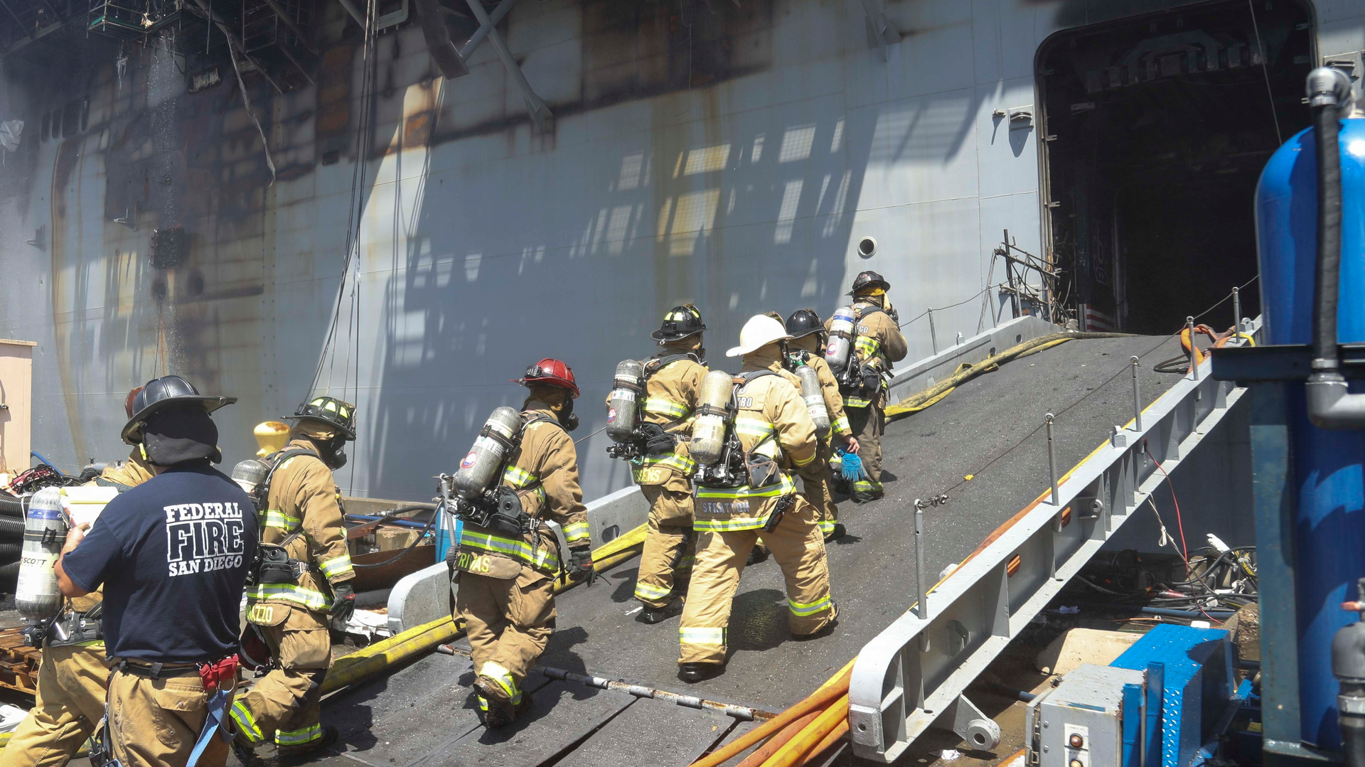 A firefighting team comprised of federal firefighters, San Diego Fire Department firefighters and sailors continue battling a fire that broke out aboard the USS Bonhomme Richard at Naval Base San Diego over the weekend.