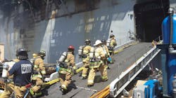 A firefighting team comprised of federal firefighters, San Diego Fire Department firefighters and sailors continue battling a fire that broke out aboard the USS Bonhomme Richard at Naval Base San Diego over the weekend.