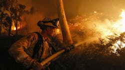 A CAL FIRE firefighter hoses a hillside along Highway 76 in Bonsall, CA, during operations against the Lilac Fire in December 2017. A CAL FIRE firefighter hoses a hillside along Highway 76 in Bonsall, CA, during operations against the Lilac Fire in December 2017.