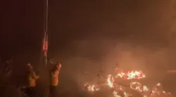 Firefighters save a U.S. flag Wednesday caught in the Lake Fire that has burned more than 10,000 acres in the Lake Hughes, CA.