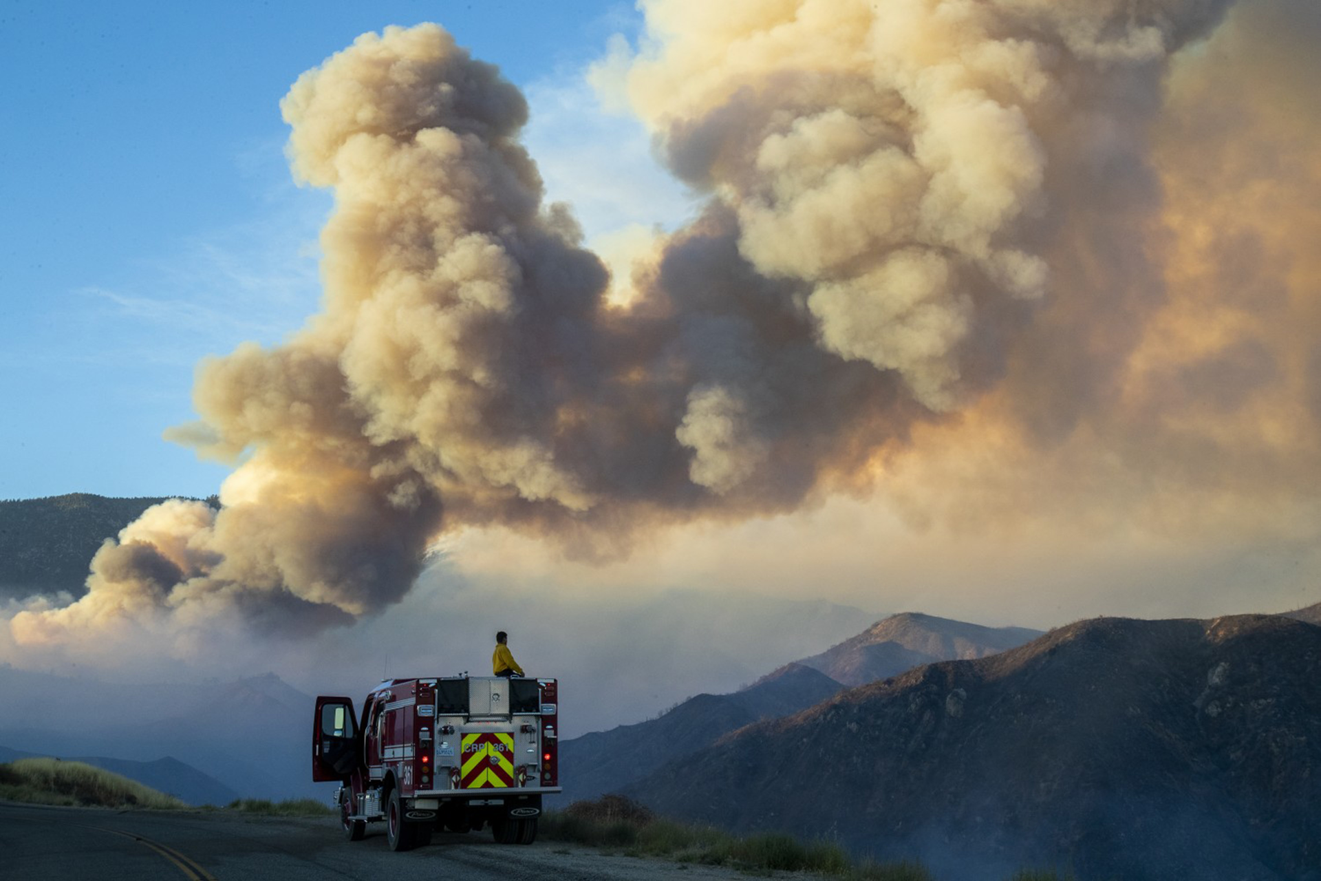 A firefighter from Carpinteria monitors a huge plume of smoke from the Apple Fire along Bluff Street, north of Banning, CA, on Sunday, Aug. 2, 2020.