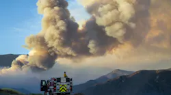 A firefighter from Carpinteria monitors a huge plume of smoke from the Apple Fire along Bluff Street, north of Banning, CA, on Sunday, Aug. 2, 2020.