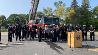 Maine Gov Janet Mills presents flowers during a Wednesday memorial ceremony to Farmington Fire Chief Terry Bell, the brother of Capt. Michael Bell, who was killed in a propane explosion last year.