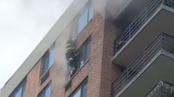 An FDNY firefighter reaches a woman on the 16th floor during a high-rise fire in Harlem on Tuesday.