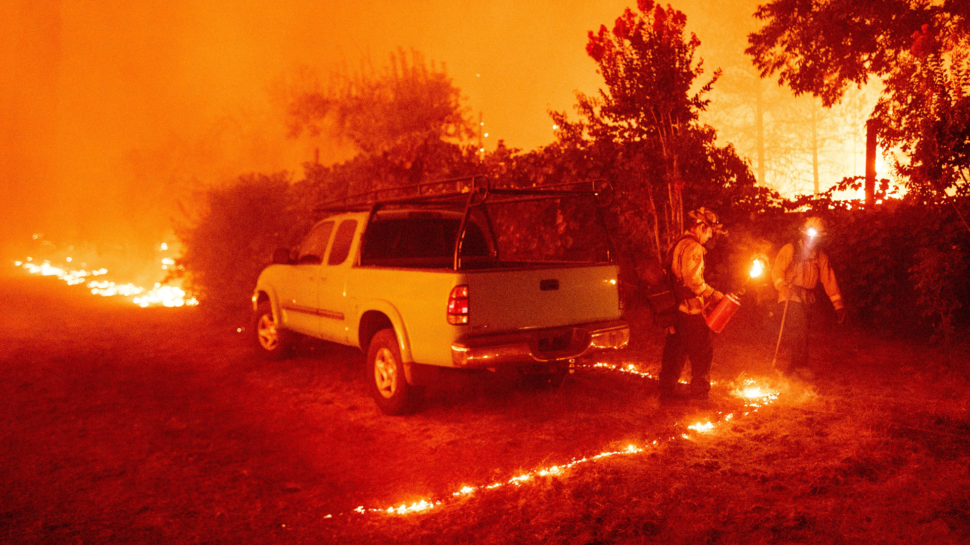 Firefighters light backfire around a vehicle during the Bear fire, part of the North Lightning Complex fires, in the Berry Creek area of unincorporated Butte County, CA, on Sept. 9, 2020.