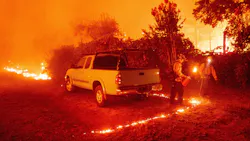 Firefighters light backfire around a vehicle during the Bear fire, part of the North Lightning Complex fires, in the Berry Creek area of unincorporated Butte County, CA, on Sept. 9, 2020.