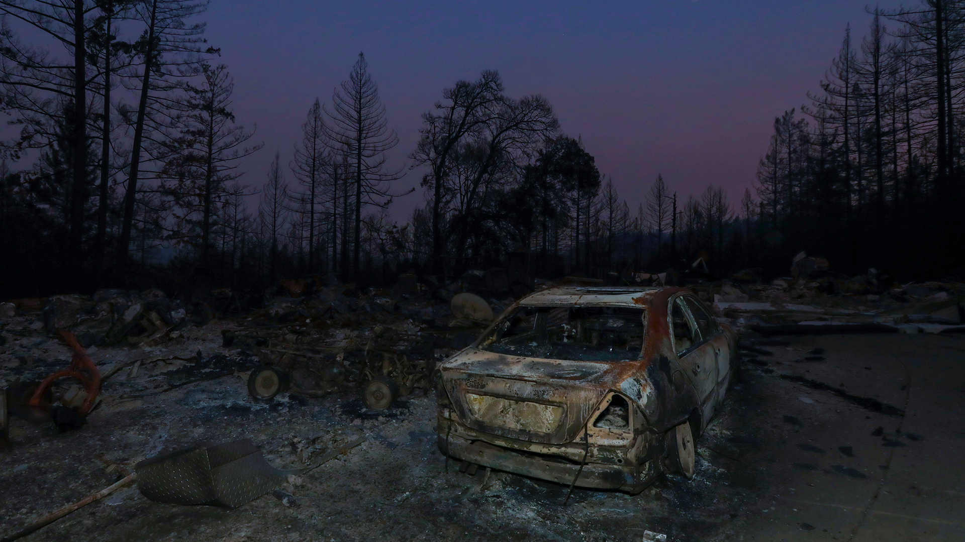 Charred remains of a structure and a vehicle hit by the CZU Lightning Complex fire in Boulder Creek, CA.