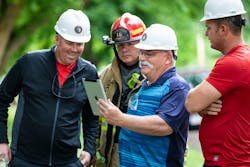 Technical panel members Greg Hubbard, Ray McCormack and Russell Gardner (front row) talk through the scenario of a single-family experiment with Jason Truesdale of the Sidney Fire Department (back row) prior to ignition in Sidney, OH.