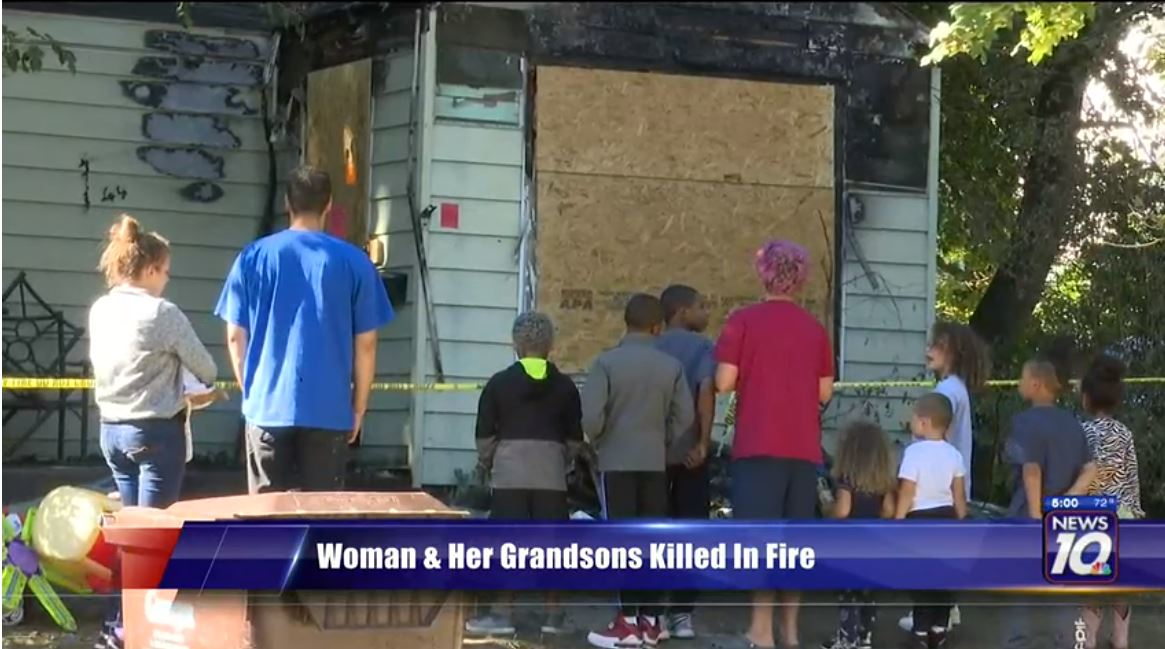 Neighbors gather at the scene after three people were killed in a Lansing house fire early Friday.