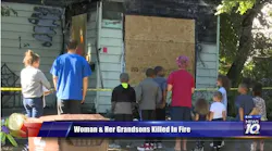 Neighbors gather at the scene after three people were killed in a Lansing house fire early Friday.
