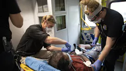 Austin-Travis County, TX, EMS paramedic practitioner Travis Baker (middle) gives a man medication as medic James Cavarretta (left) and Ashley Faulstich assist.