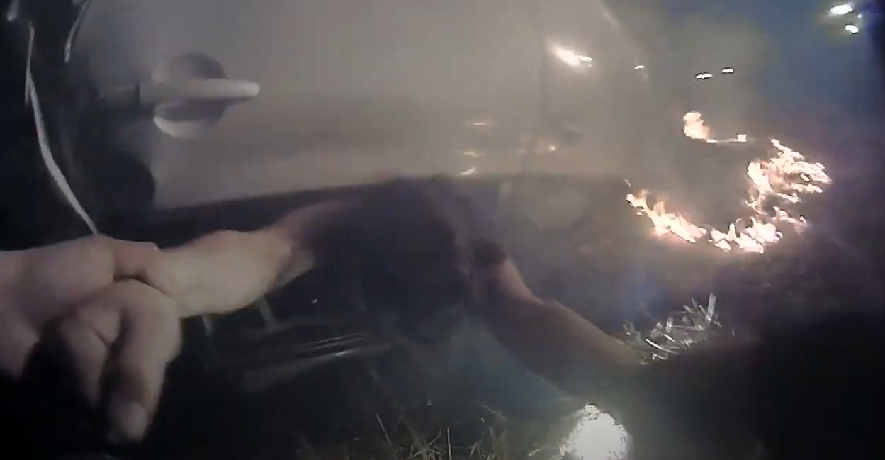 Davis, CA, Police Cpl. Pheng Ly pulls a driver from her overturned car moments after a fiery crash along Interstate 80 on Saturday. The dramatic rescue was captured by Ly's body and dashboard cameras.