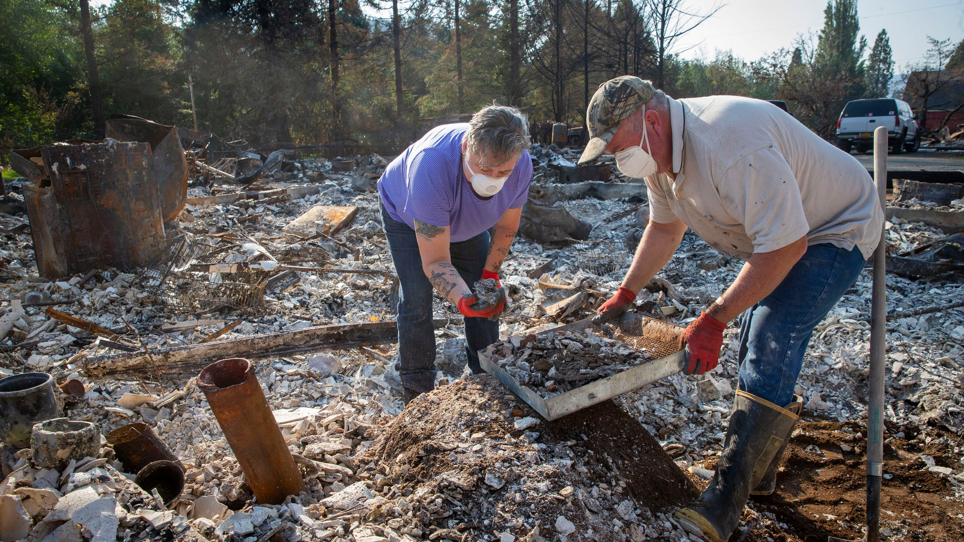 Upper McKenzie, OR, Fire Chief Christiana Rainbow Plews (left) works with Clayton Canfield as they sift through the debris of her home this week in Vida.